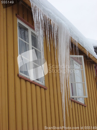 Image of Icicle hanging from the roof of a yellow house