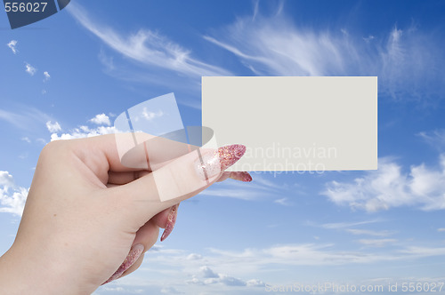 Image of card in a hand on sky background