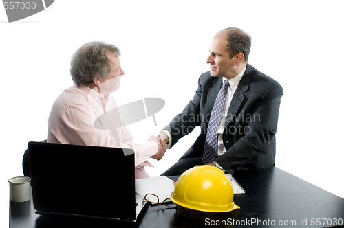 Image of two business partners at desk shaking hands