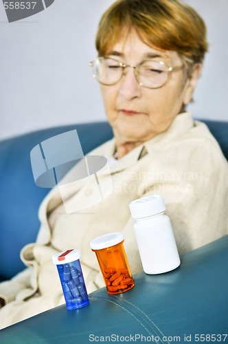 Image of Elderly woman looking at pill bottles