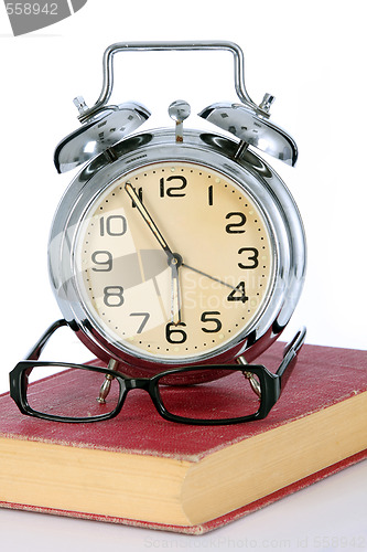 Image of book with alarm clock and eyeglasses 