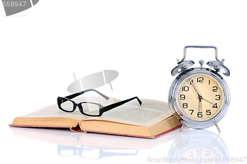 Image of book with alarm clock and eyeglasses 