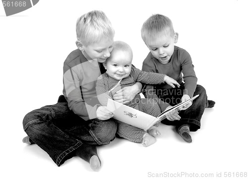 Image of Two young brothers reading for their baby sister