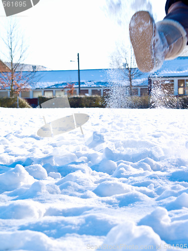 Image of Boot kicking up snow in a field