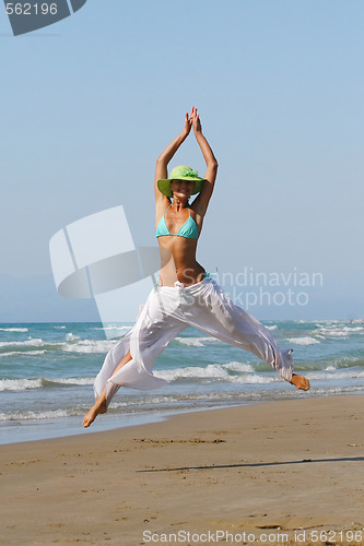 Image of Beautiful young woman jumping on a beach in Greece