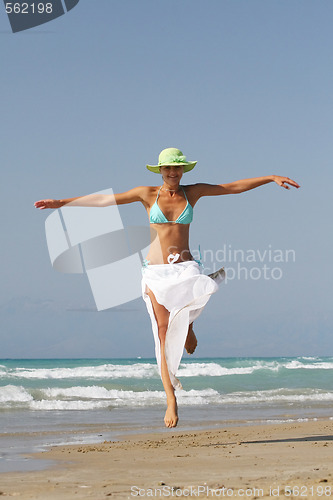 Image of Beautiful young woman jumping on a beach in Greece