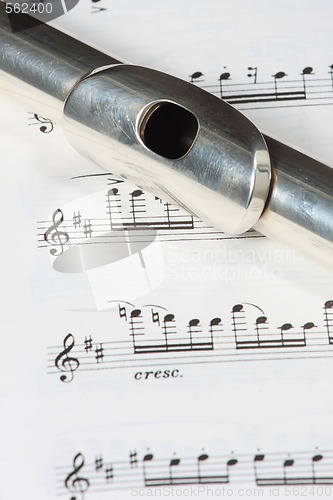 Image of Silver flute instrument resting on a music score