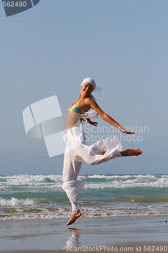 Image of Beautiful young woman jumping on a beach in Greece