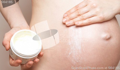 Image of pregnant woman holding body lotion