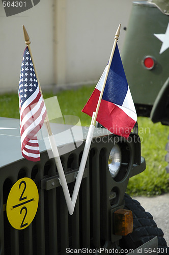 Image of US and french flags front of an old jeep