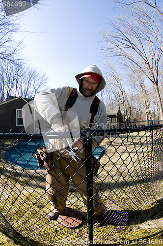 Image of   workman repairing building chain link fence
