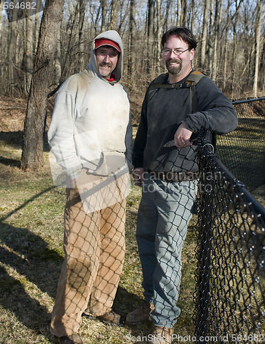 Image of two workmen repairing chain link fence