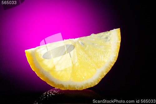Image of close-up of lemon slice on table glass and violet background
