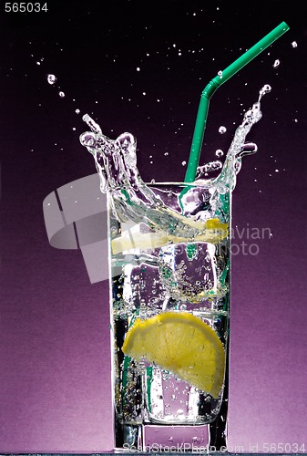 Image of sliced lemon falling in glass of alcoholic drink with ice cubes 