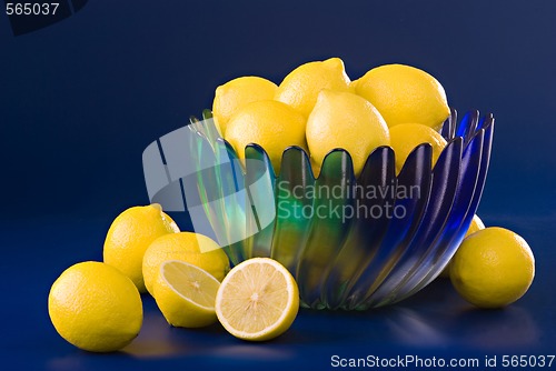 Image of lemons in blue green bowl on blue background