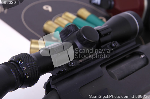 Image of Shotgun with a rifle scope target and shotshell