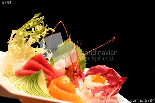 Image of Assortment of sushi on a plate against a black background.