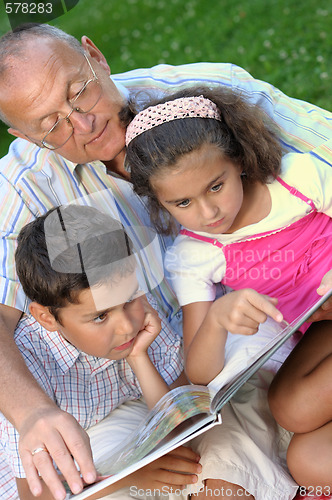 Image of Grandfather and kids reading book 