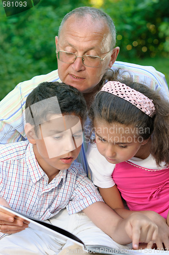 Image of Grandfather and kids reading book