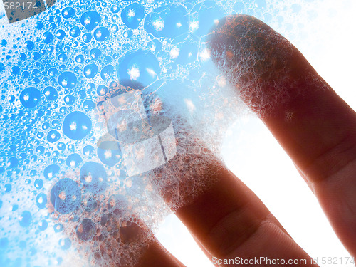 Image of Fingers hold blue soap bubbles