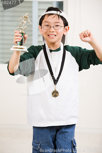Image of Winning boy with his medal and trophy
