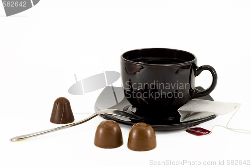 Image of Tea cup, teaspoon and chocolates isolated