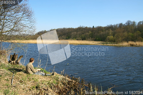 Image of Fisherman sitting on the river shore