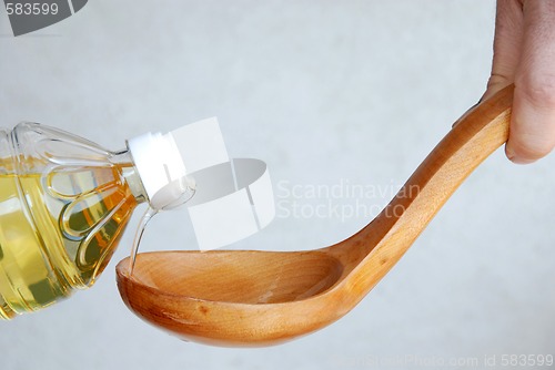 Image of Pouring oil in wooden spoon