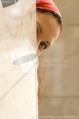 Image of woman looking behind a wall
