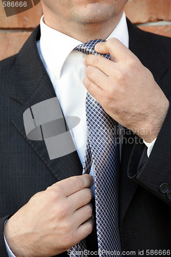 Image of Businessman adjusting necktie