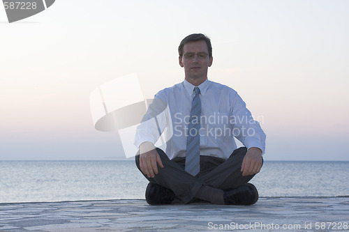 Image of Businessman meditating by the sea