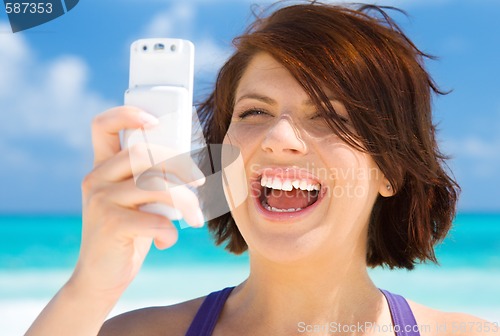 Image of happy woman with phone on the beach