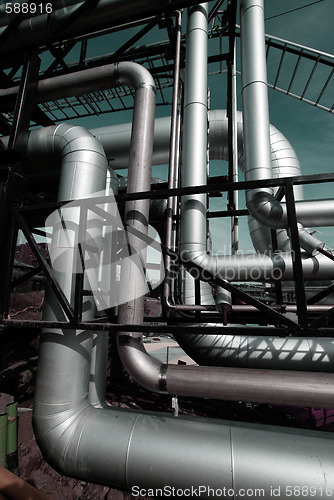 Image of industrial pipelines on pipe-bridge against blue sky    