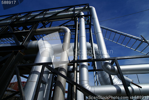 Image of industrial pipelines on pipe-bridge against blue sky   