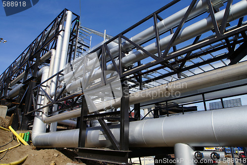 Image of industrial pipelines on pipe-bridge against blue sky   