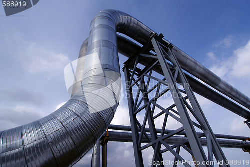 Image of industrial pipelines on pipe-bridge against blue sky   