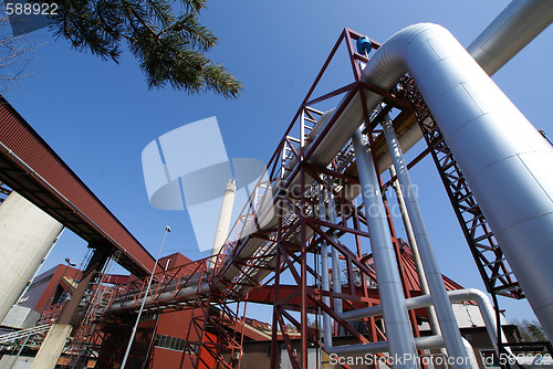 Image of industrial pipelines on pipe-bridge against blue sky      