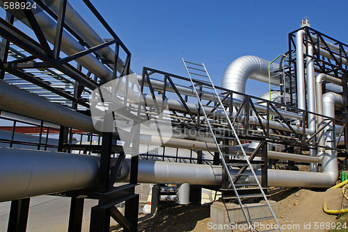 Image of industrial pipelines on pipe-bridge against blue sky 