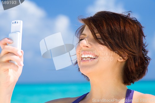 Image of happy woman with phone on the beach