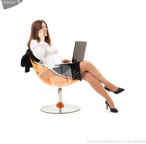 Image of businesswoman in chair with laptop and phone