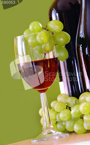 Image of Red wine with grapes cluster over green