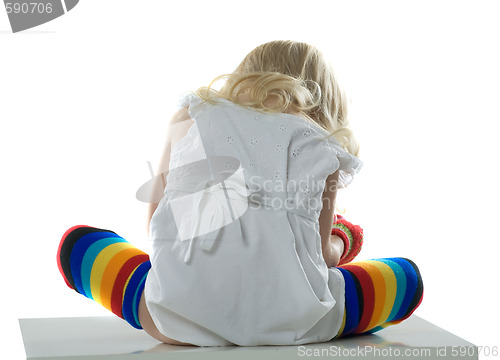 Image of little girl sits back on white chair