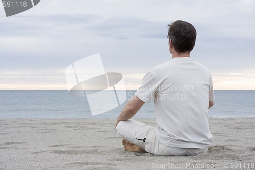 Image of Man meditating on beach