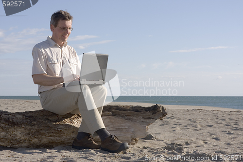 Image of Man working with laptop on beach