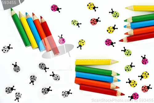 Image of Multicolored crayons and ladybirds composition