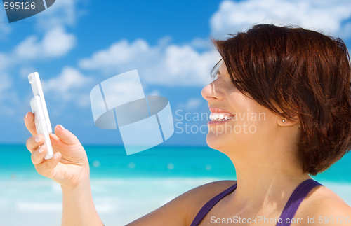 Image of happy woman with phone on the beach