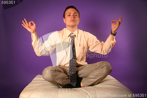 Image of Young businessman meditating on sofa