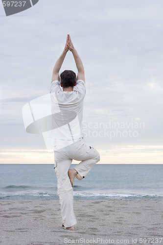 Image of Man doing yoga on beach