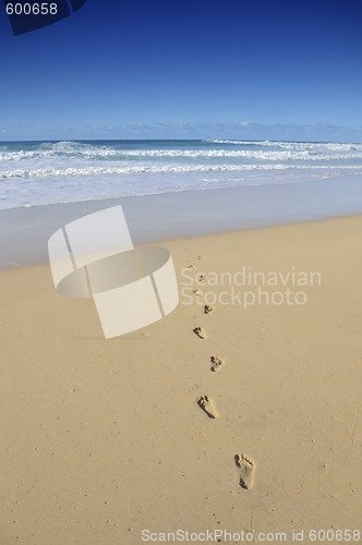 Image of Footsteps on a white sand beach disappearing in the sea