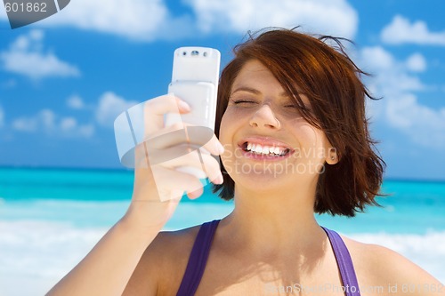 Image of happy woman with phone on the beach